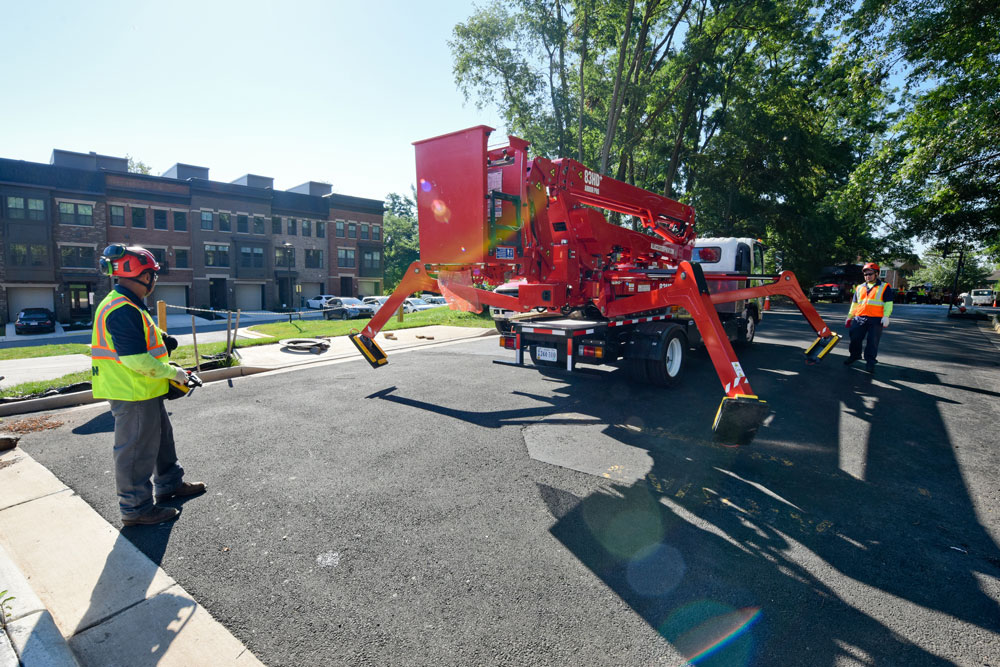 Granite Hills crew setting up a truck-mounted tree lift with its outriggers extended on a residential street