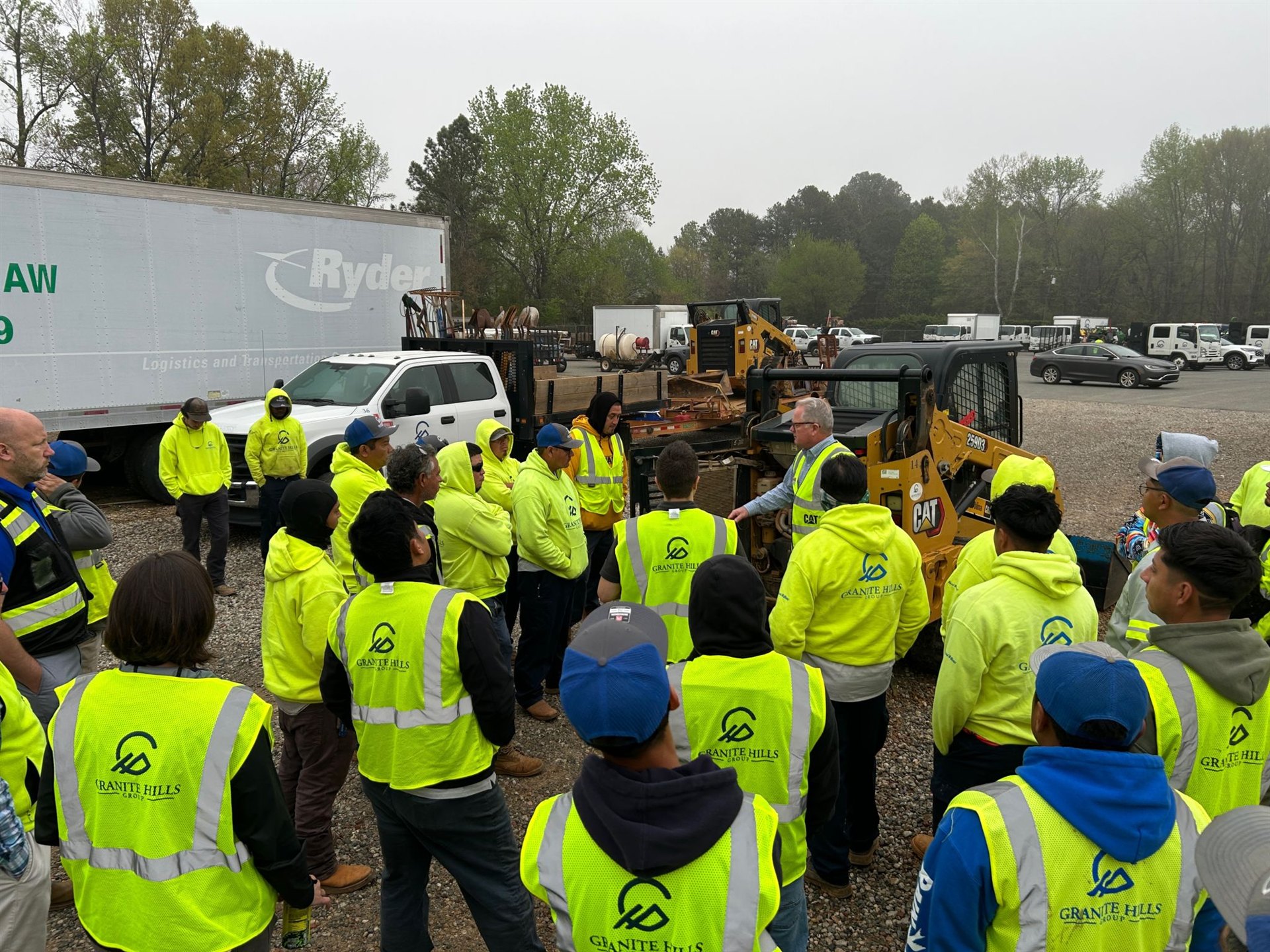 Granite Hills Charlotte crew members gathered around a skid steer for an equipment training session
