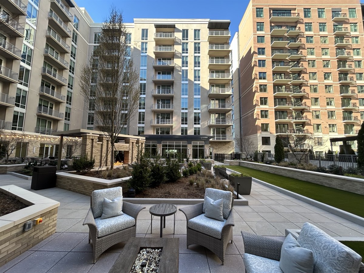 Completed courtyard landscape with raised planters, fire pit seating and lawn at a residential high-rise