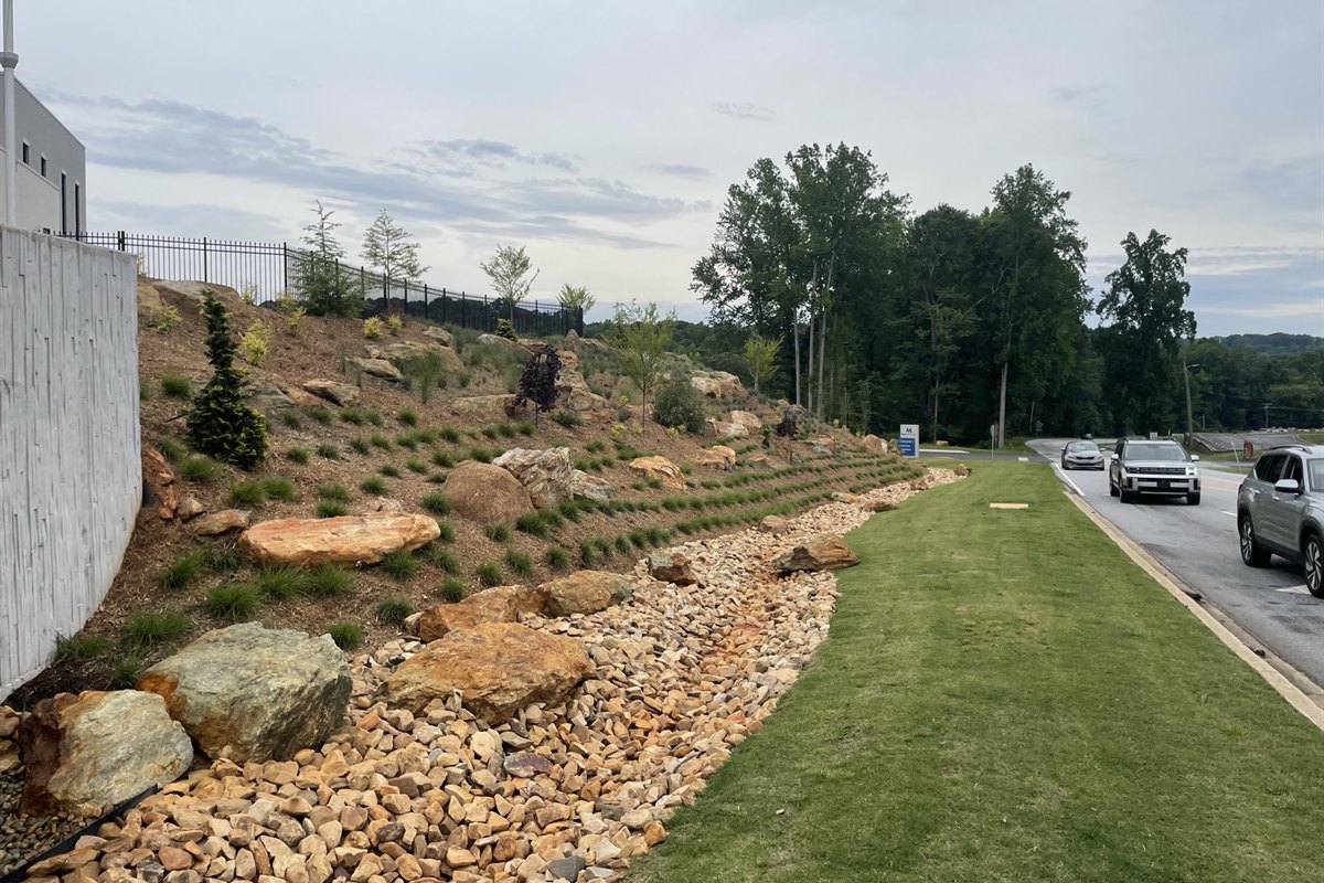 Newly installed boulder slope, dry creek bed and plantings along a commercial frontage