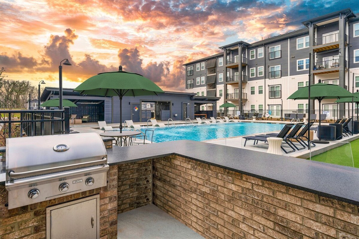 Pool deck with a brick outdoor kitchen at a multifamily amenity