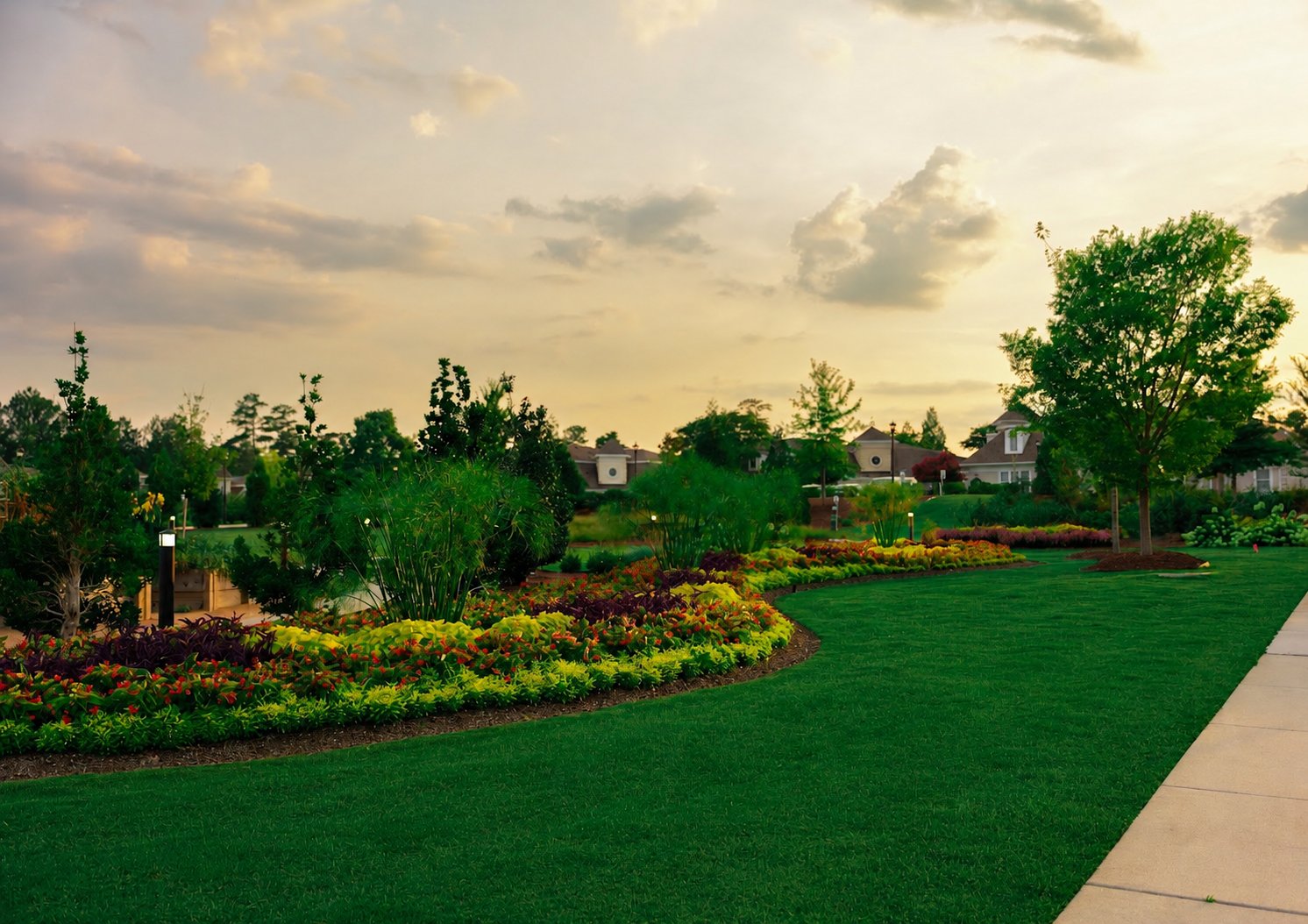 Landscaped community grounds with curved flower beds and manicured lawn at sunset