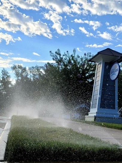 Irrigation spray heads watering turf along a community entrance