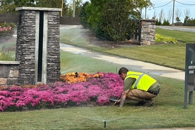 Granite Hills irrigation technician adjusting a spray head beside a seasonal color bed