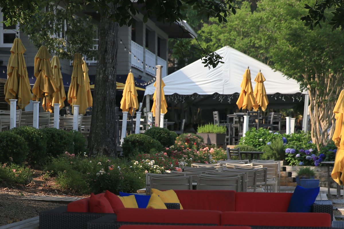 Outdoor dining terrace framed by planted beds of roses, hydrangeas and shrubs