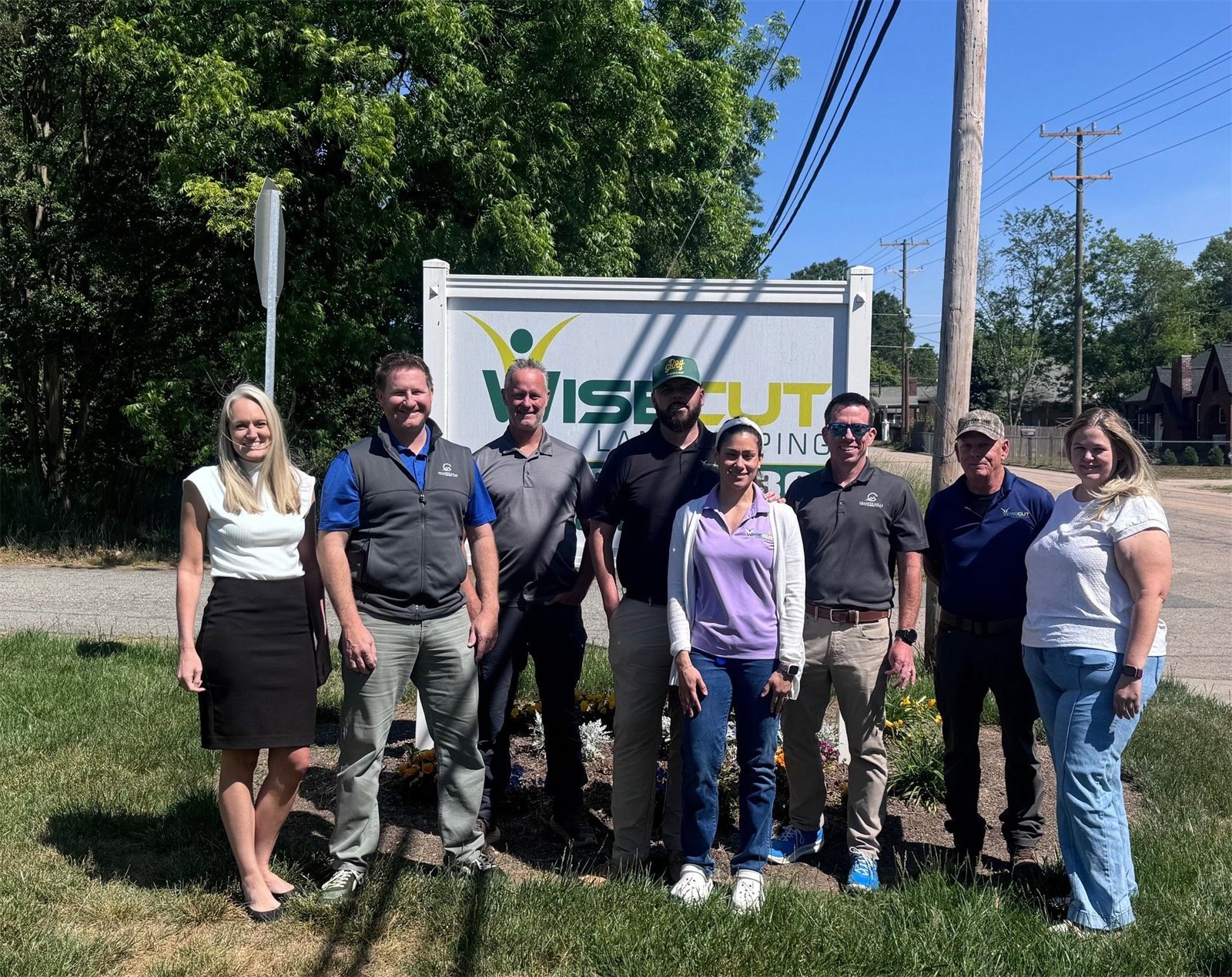 The Wise Cut and Granite Hills teams at the Wise Cut Landscaping sign in Kannapolis