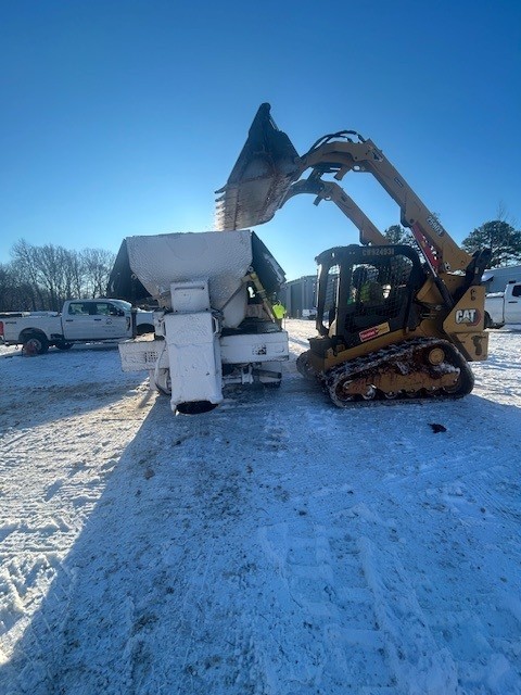 Loader filling a truck-mounted salt spreader before a winter event