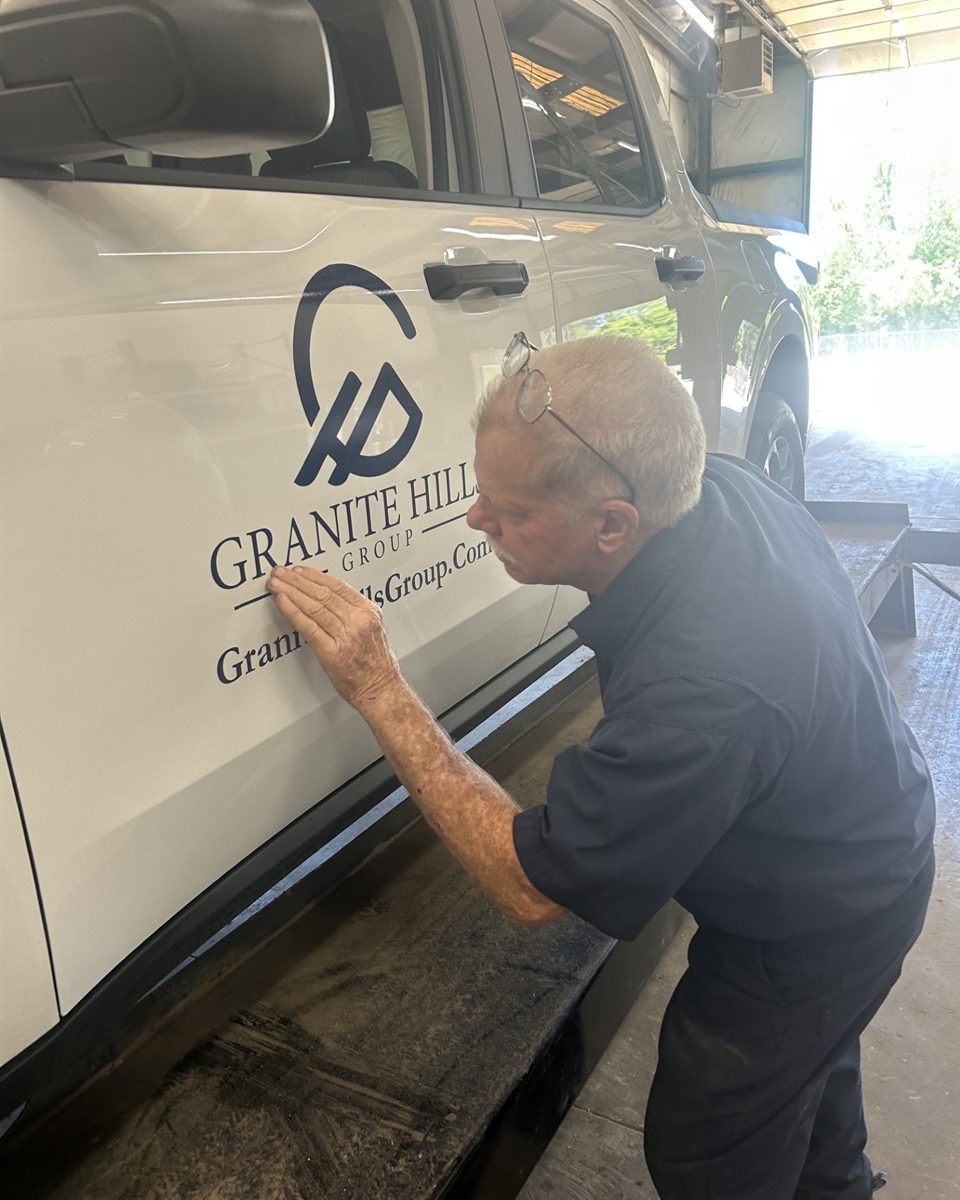 A Granite Hills team member applying the Granite Hills Group logo to a company truck.