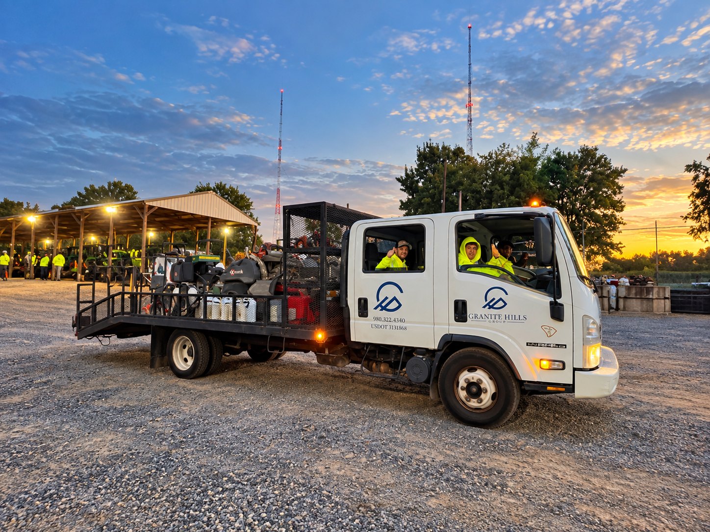 Granite Hills Upstate crew members waving from a company truck loaded with mowers at sunrise