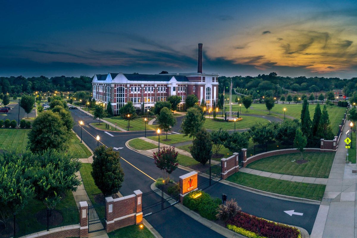 Landscaped entrance, lawns and tree-lined drive at a college campus at dusk